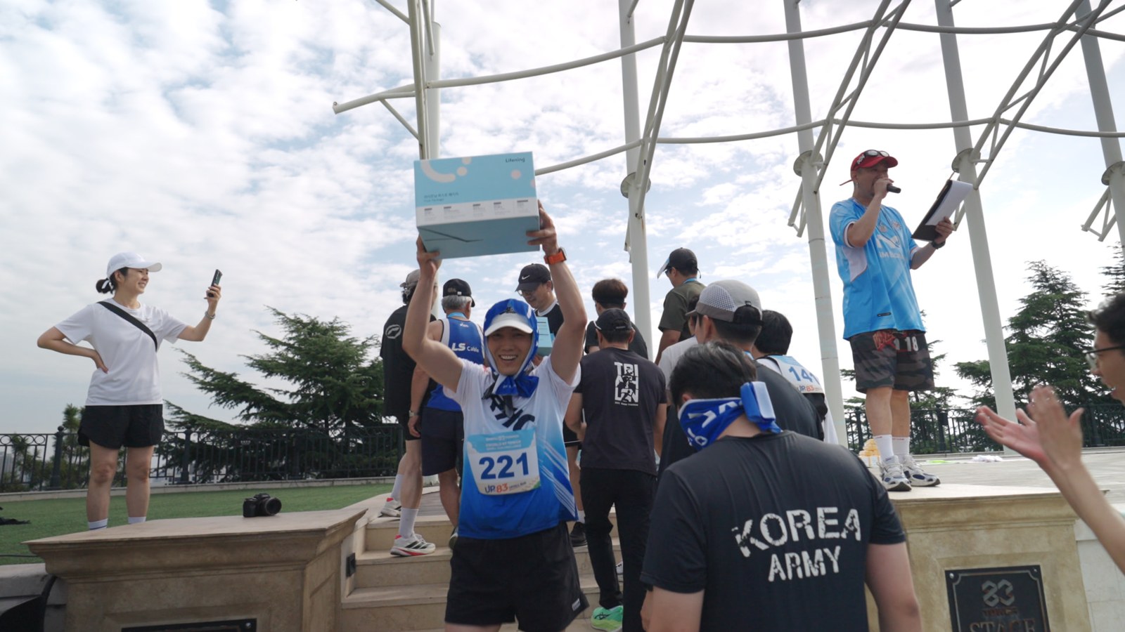 무대에서 럭키드로우 경품을 받아 들고 기뻐하는 1회차 참가자
